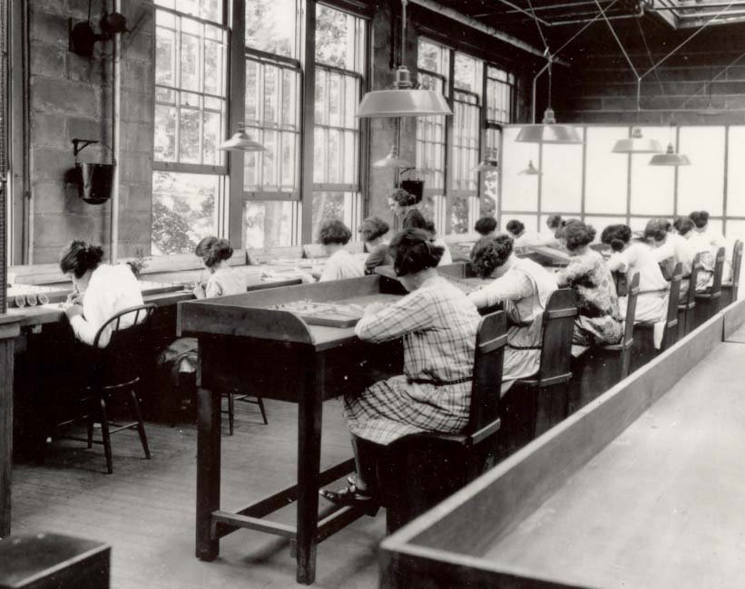 Historical photograph of women painting radium watch dials inside a factory during the 1920s.